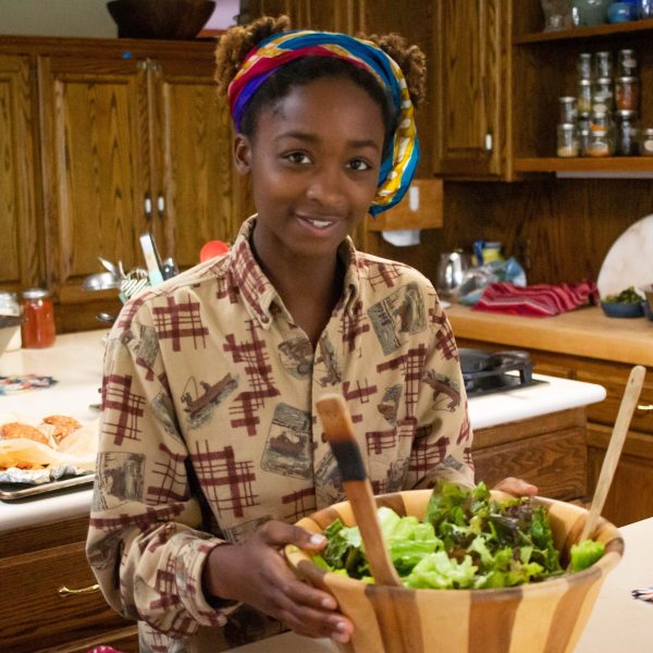 Alanna smiles at the camera while holding a bowl full of salad