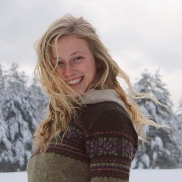 Charly smiling at the camera with snowy trees in the background