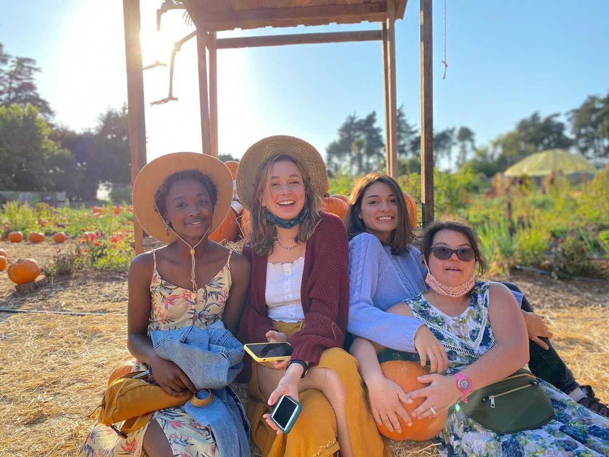 Hazel, Alanna, and friends smiling at the camera while holding a pumpkin