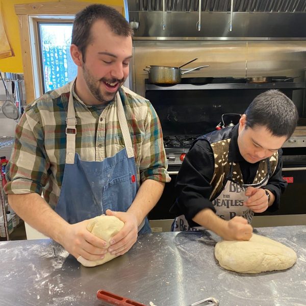 Nathan and a Camphill resident smiling while kneading dough