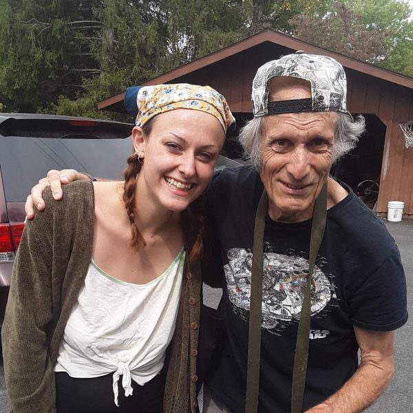 Sarah and a Camphill resident smiling at the camera with their arms around each other