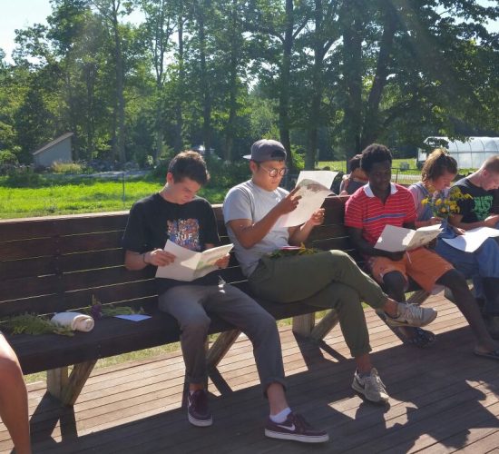 A group of volunteers sit on a bench reading letters.