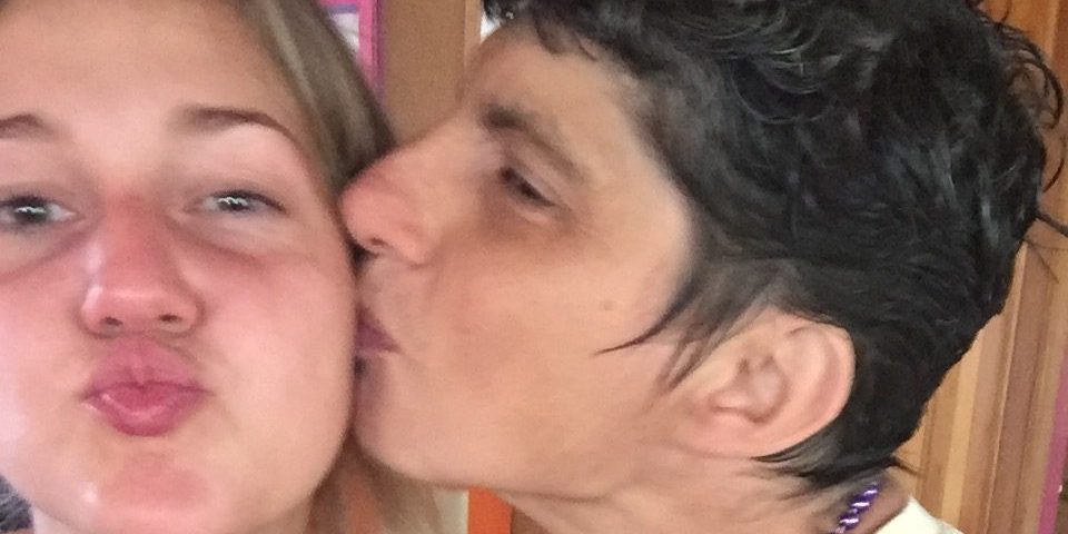 Close up selfie of Anna and a Camphill resident. Anna's lips are puckered and the resident is kissing her on the cheek