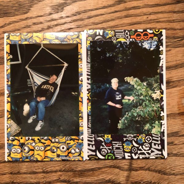 Two polaroids lying upon a wooden table. One is of a Delaney smiling in a hammock chair in the dark. The other is of a Asher with his hand inside of a bush with trees in the background. Both people are smiling at the camera. The polaroid pictures are decorated with Minion characters from the film Despicable Me.