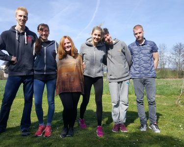 Six Camphill alumni stand in a grassy area smiling together