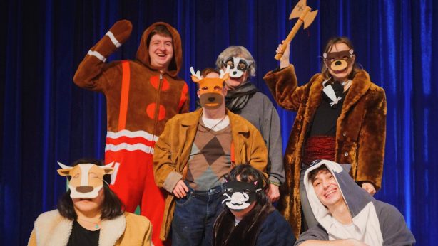Nicolo is pictured with 6 of his castmates from Jimmys Journey, smiling in front of a blue curtain. They are all dressed as animals.
